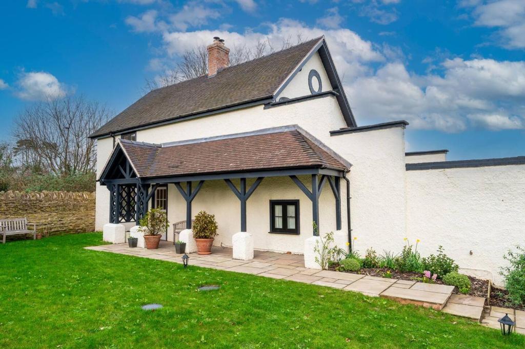 een wit huis met een zwart dak en een tuin bij Pass the Keys Garden Cottage · Beautiful cottage nestled in 80 acres of parkland in Diddlebury