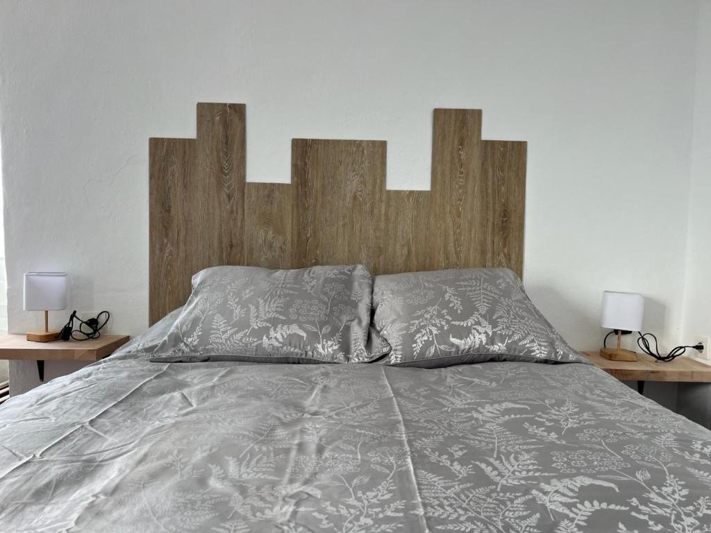 a bed with a wooden head board and two lamps at ALMAFUERTE in Mijas