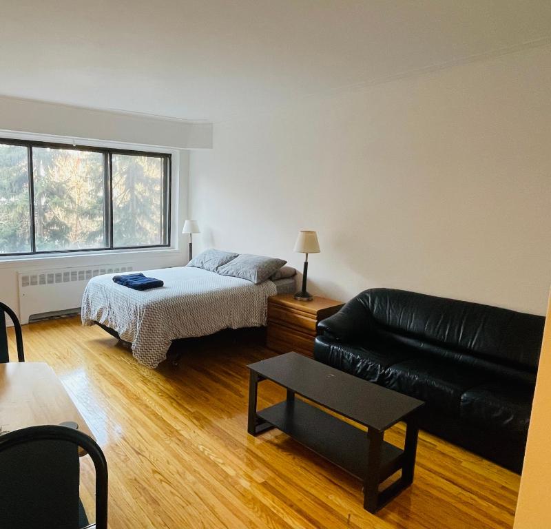 sala de estar con cama y sofá de cuero negro en Stylish Montreal Apartment: Comfortable Stay in the Golden Square Mile, en Montreal