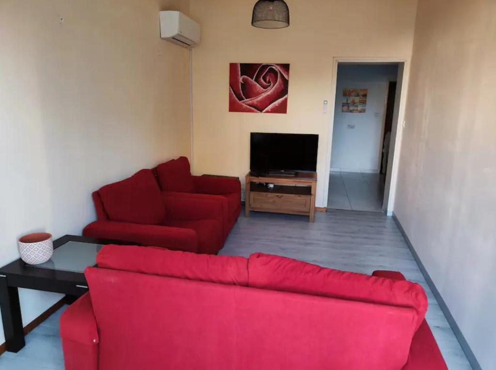 uma sala de estar com um sofá vermelho e uma televisão em Art house residence em Limassol