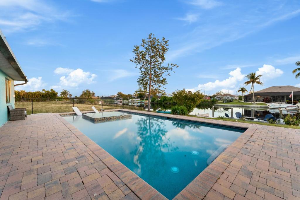 uma grande piscina com um passadiço de tijolos ao lado de uma casa em CapeCoral Waterfront Villa - Heated Pool & Jacuzzi em Cape Coral