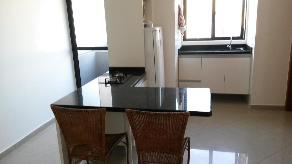 a kitchen with a black counter and three chairs at Apartamento Central Curitiba in Curitiba