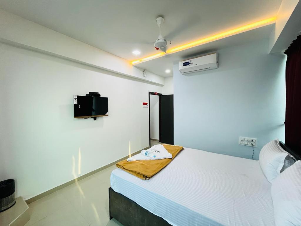 Habitación con cama y TV en la pared. en Hotel Pleasure, en Surat