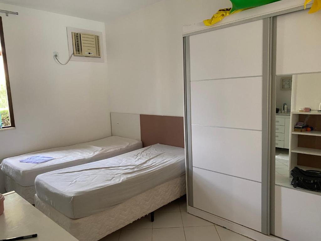 Habitación pequeña con 2 camas y espejo. en Casa 08 Quadra 06 Cond. Viva Vida, en Aracaju