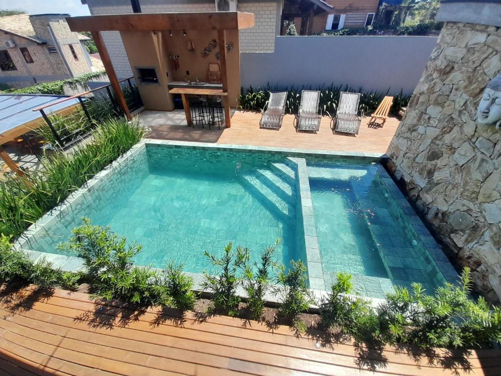 una piscina en una terraza con sillas alrededor en Pousada Kirana, en Praia do Rosa