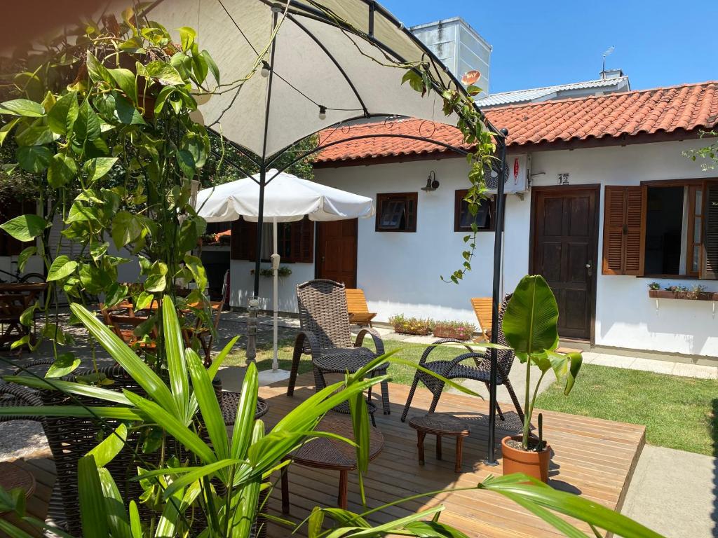 eine Außenterrasse mit Stühlen und einem Sonnenschirm in der Unterkunft Quintal da Casa in Garopaba