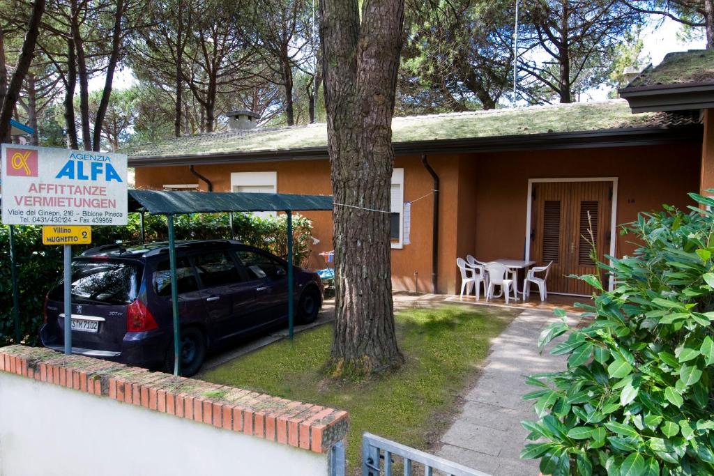 a car parked in front of a house with a tree at Mughetto in Bibione