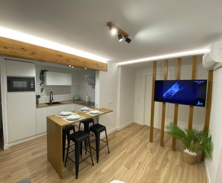 a kitchen with a bar with stools and a flat screen tv at LAR DE SEFA in Redondela