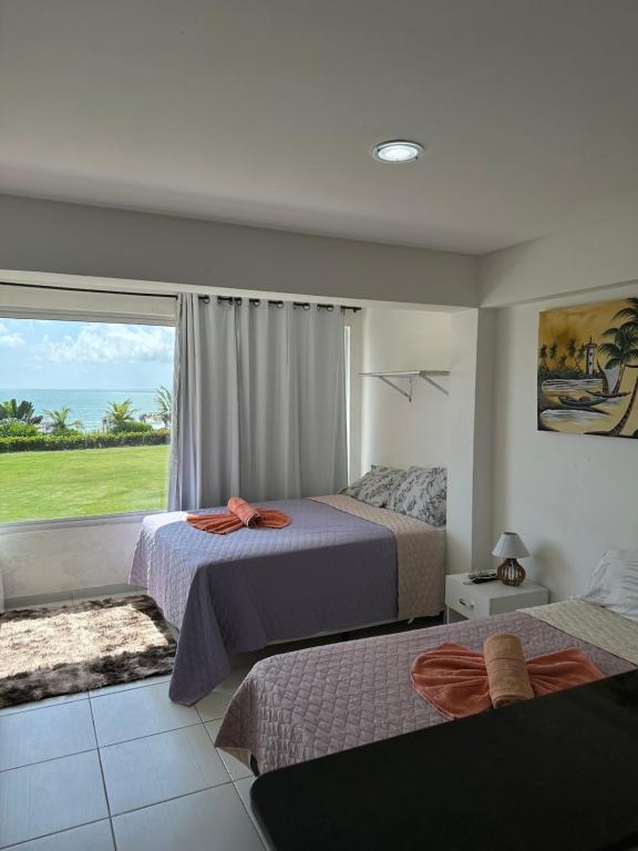 een slaapkamer met 2 bedden en een groot raam bij Pousada do mirante in Cabo de Santo Agostinho
