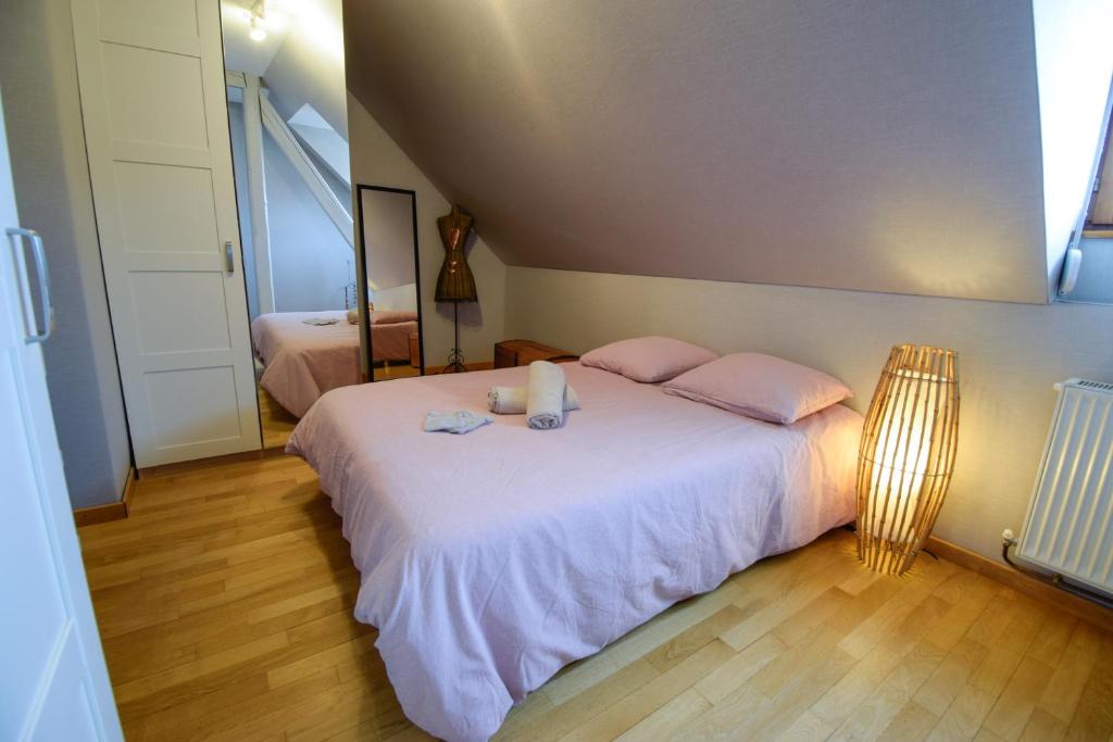 1 dormitorio con 1 cama blanca grande con almohadas rosas en Gîte de la tour des Fripons. en Kientzheim