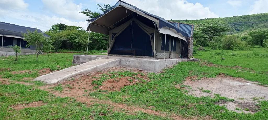 una tienda en un campo junto a un edificio en orkaria safari mara camp, en Sekenani