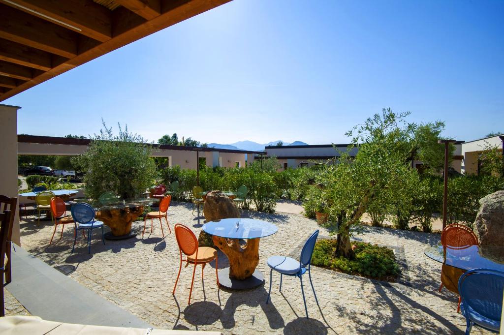 un patio con mesa, sillas y árboles en Hotel Barbagia en Dorgali