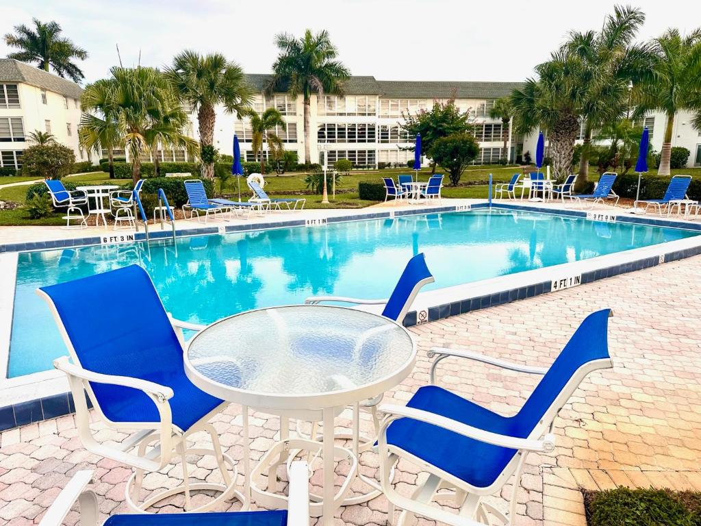 a table and chairs next to a swimming pool at Stunning 2-Bd Condo Naples, 55+, pool, Chickee, golf in Naples