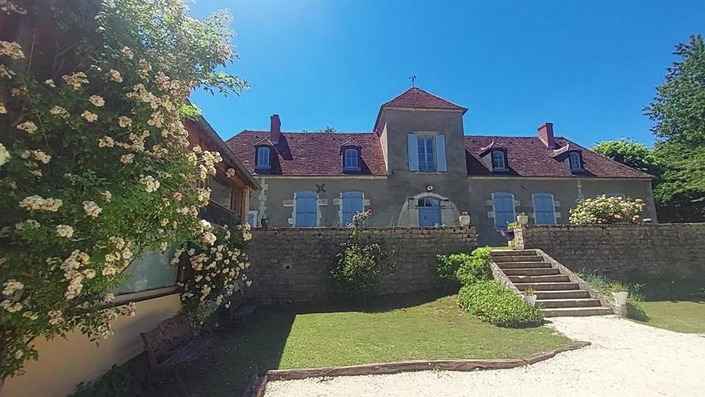 a large house with a brick wall and flowers at La Cuvellerie in Narcy