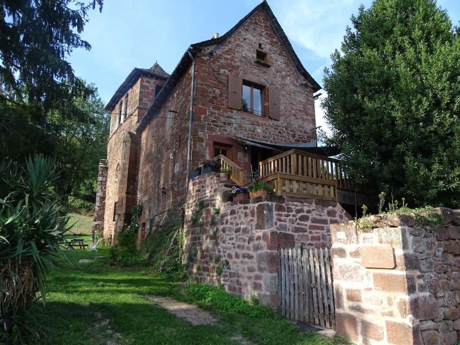 an old brick building with a deck on the side of it at Gîte de Ségonzac in Villecomtal