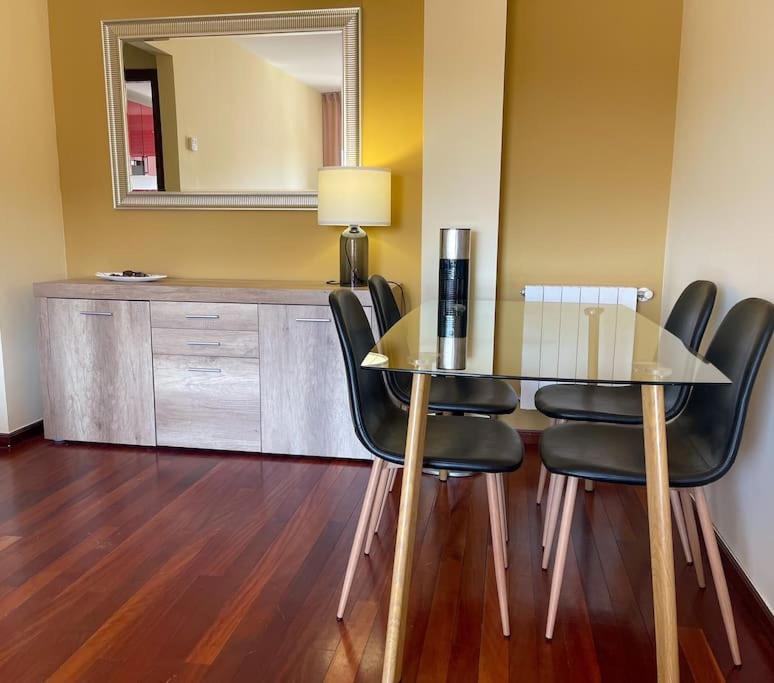 a dining room table with black chairs and a mirror at El apartamento de Adriana en Torrelavega. in Torrelavega