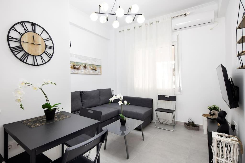 a living room with a couch and a table and a clock at A modern apartment in the heart of Athens in Athens