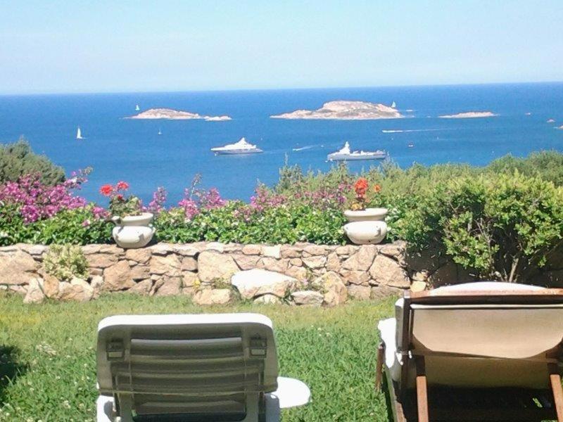 duas cadeiras de jardim sentadas na relva perto do oceano em Villa Emerald em Porto Cervo