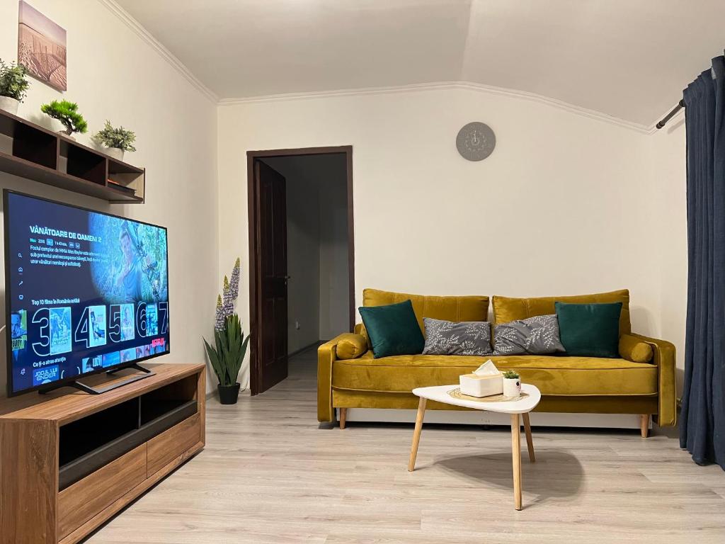 a living room with a yellow couch and a tv at NDL Downtown in Cluj-Napoca