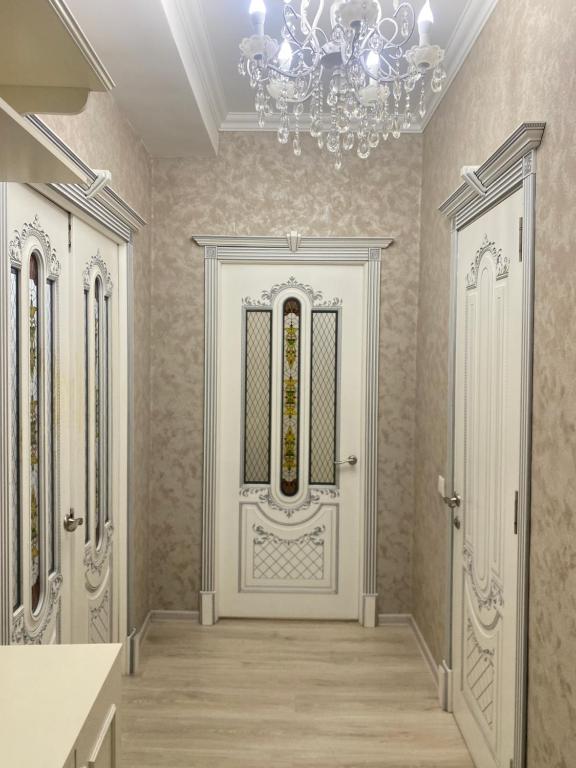 a hallway with a white door with a chandelier at 4х комнатная квартира in Bishkek