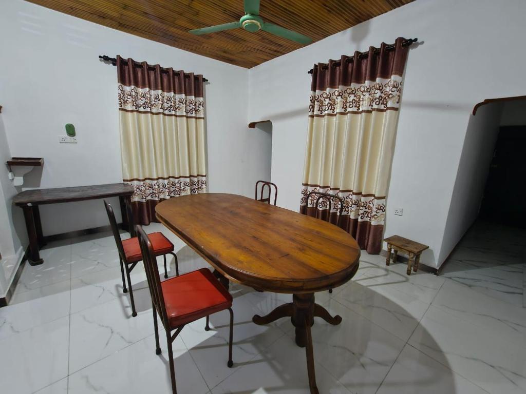 a wooden table and chairs in a room with curtains at SSM GUEST INN in Trincomalee