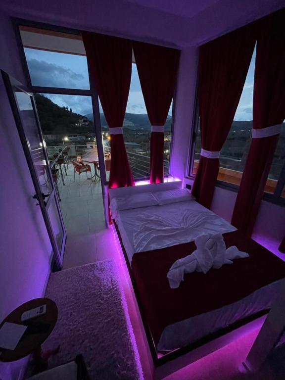 een slaapkamer met een bed met een paars licht bij Hotel Bar Restaurant Mete in Peshkëpi
