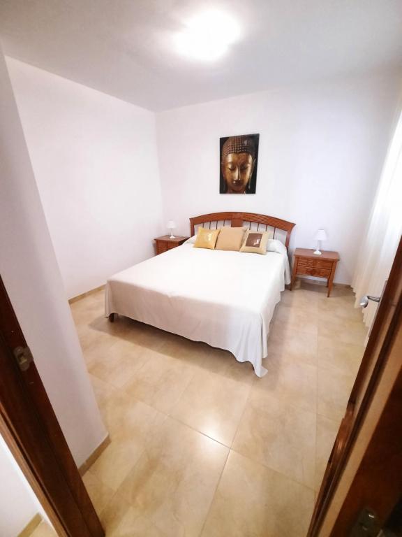 Un dormitorio con una cama blanca y una pintura en la pared en Amplio apartamento céntrico, en Peñíscola