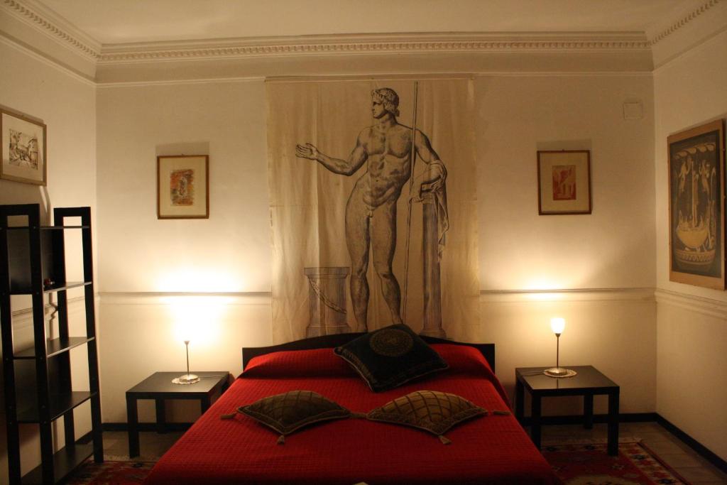 Un dormitorio con una cama roja con una estatua en la pared en B&B degli Ottimati, en Reggio Calabria