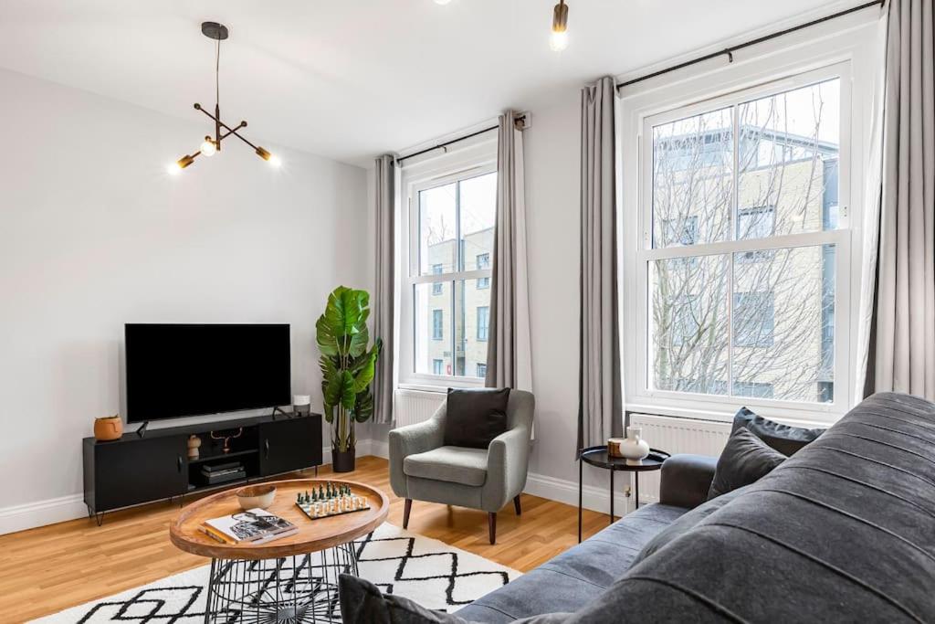 sala de estar con sofá, TV y 2 ventanas en Modern 2 Bedroom Townhouse Flat in King’s Cross, en Londres