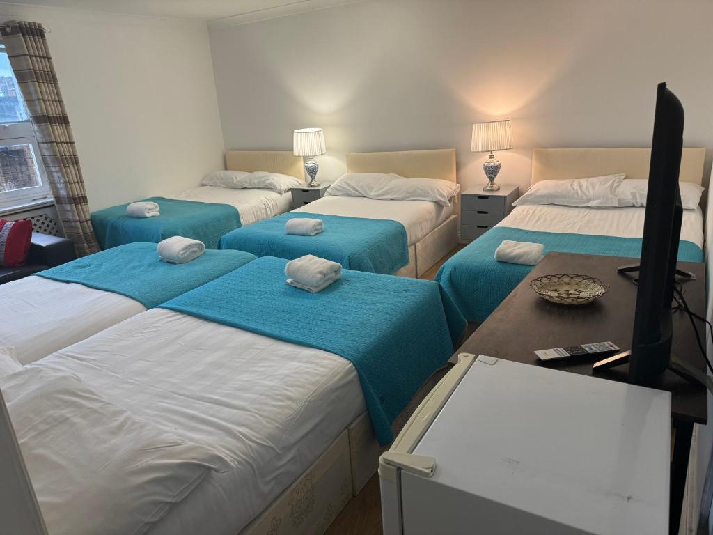 een kamer met 4 bedden met blauwe lakens bij King garden hotel in Londen