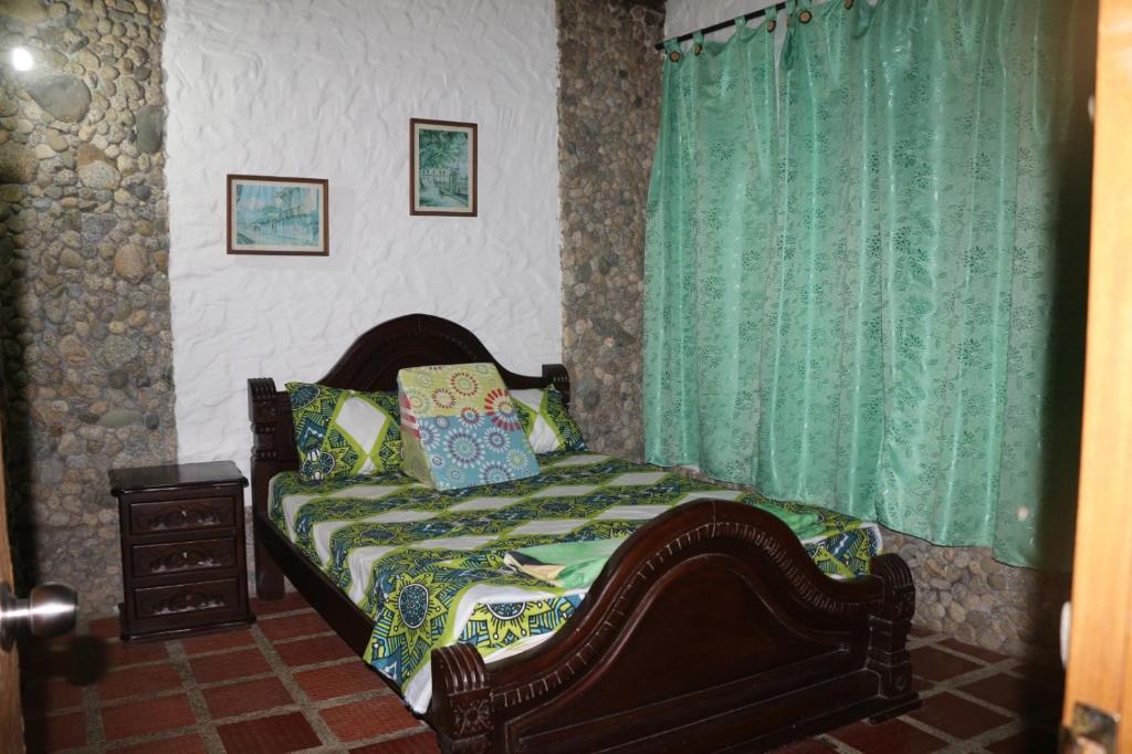 サン・ラファエルにあるNaturilandiaのベッドルーム1室(緑のカーテン付きのベッド1台付)