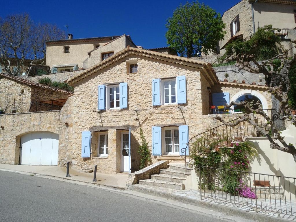 a large stone house with blue windows and stairs at La maison de Daniel - Esparron-de-Verdon in Esparron-de-Verdon