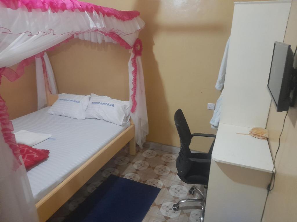 Piccola camera con letto e scrivania. di Prestige Guest House a Mariakani