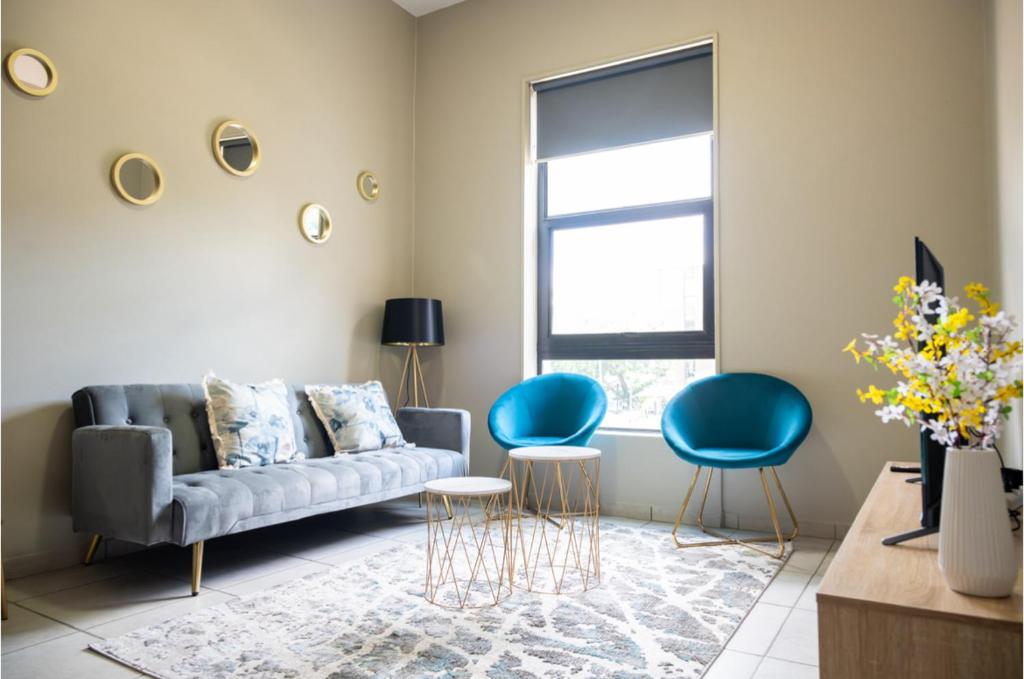sala de estar con sofá y 2 sillas en Rosebank Apartment the Bolton 27 en Johannesburgo
