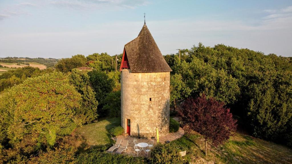 stary budynek z wieżą na szczycie wzgórza w obiekcie Idéal pour 2 - Moulin avec bain nordique et vue panoramique w mieście Galapian