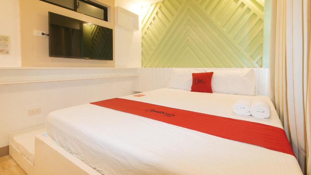 a bedroom with a white bed with a red pillow at RedDoorz @ Innzz Apartel in Davao City