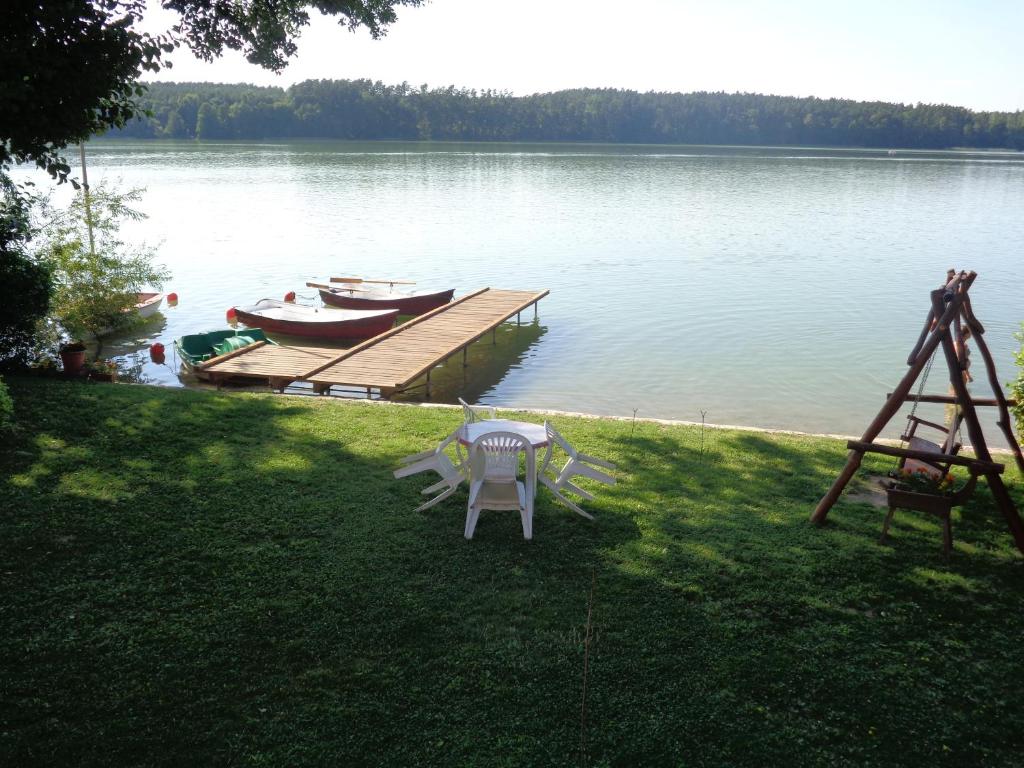 a dock with a table and a boat on the water at Domek nad jeziorem Mazury Kobyłocha 13a in Szczytno