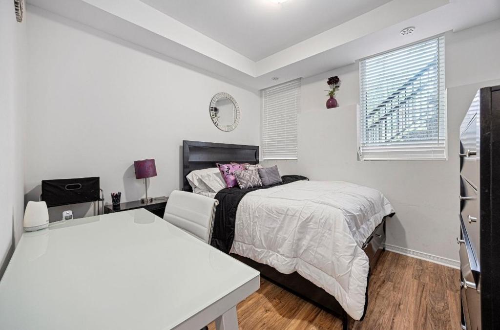 a white bedroom with a bed and a table at Cozy Private Room, Walk to Wilson Station in Toronto