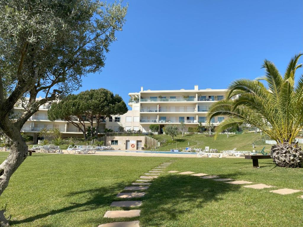 um parque com um edifício e palmeiras e um edifício em Charmant appartement a 1km de la plage, avec piscine a Albufeira em Albufeira