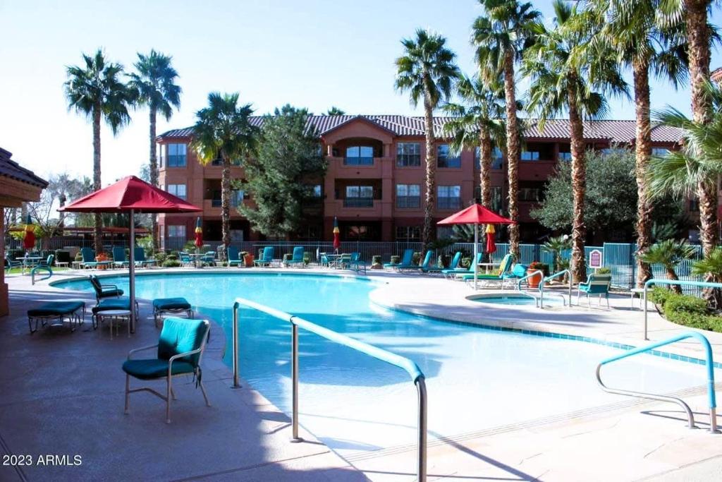 a large swimming pool with chairs and palm trees at Sun City Grand Oasis: Luxury Condo Living in La Solana in Surprise