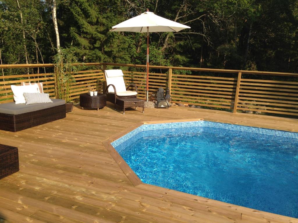 a swimming pool on a wooden deck with an umbrella at Charmigt hus på Vindö in Stockholm