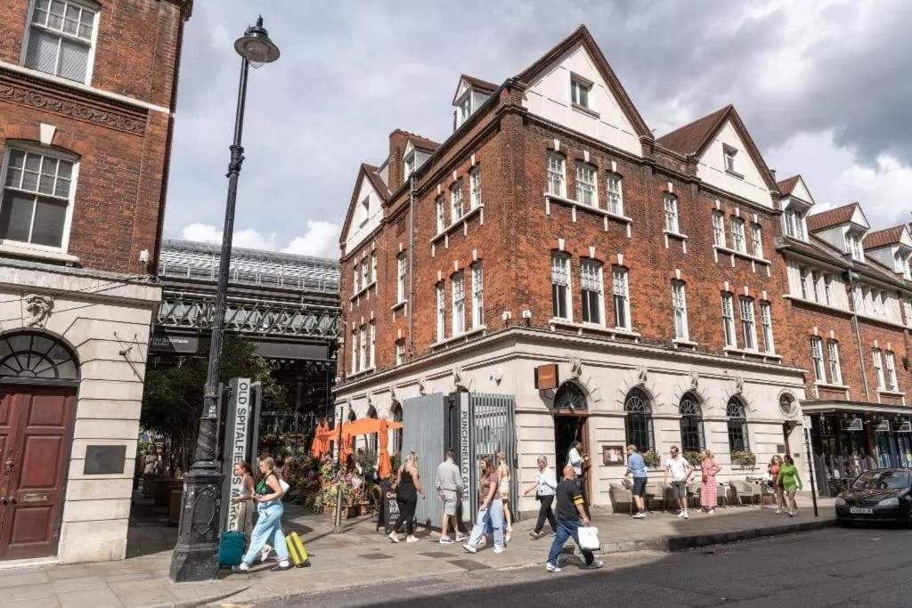 a group of people walking down a street in front of a building at Stylist 2 Bedroom Apartment in Central London in London