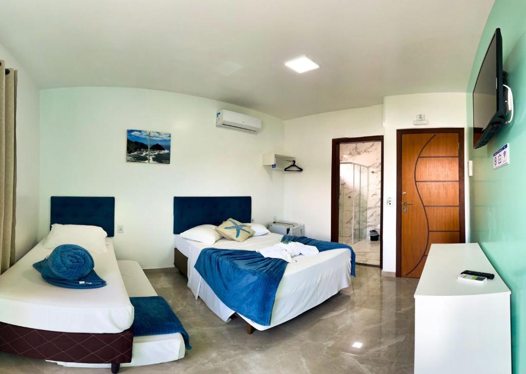 a bedroom with two beds and a door to a room at Pousada Mar de Luna in Penha