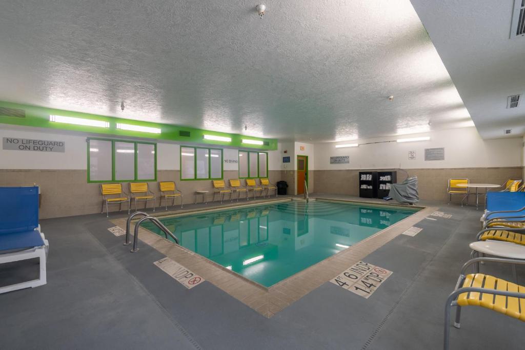 a swimming pool in a gym with chairs and tables at Wingate by Wyndham Great Falls in Great Falls
