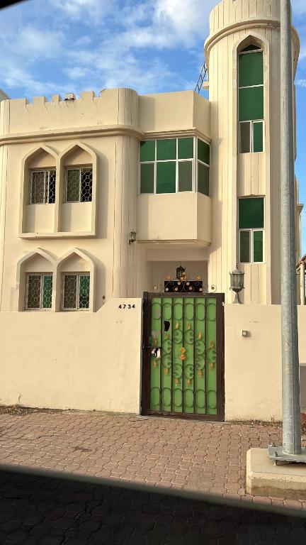 a building with a green door in front of it at Basil Hostel in Muscat
