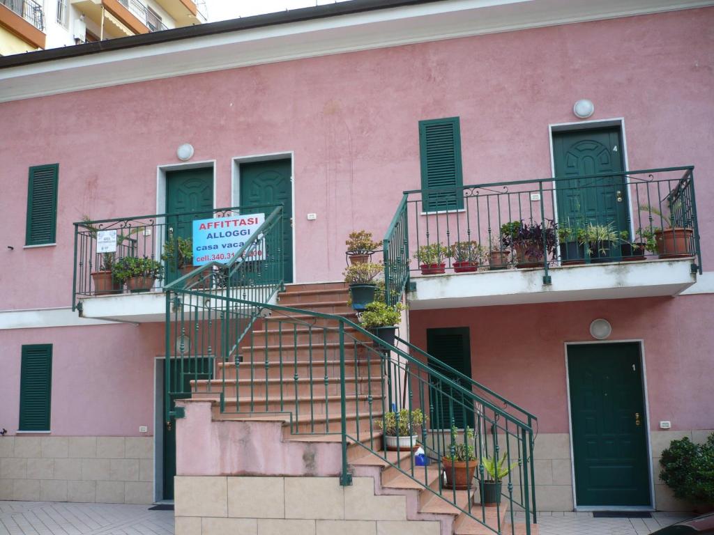 un bâtiment rose avec des escaliers et des plantes en pot dans l'établissement Villamareblu, à Vintimille