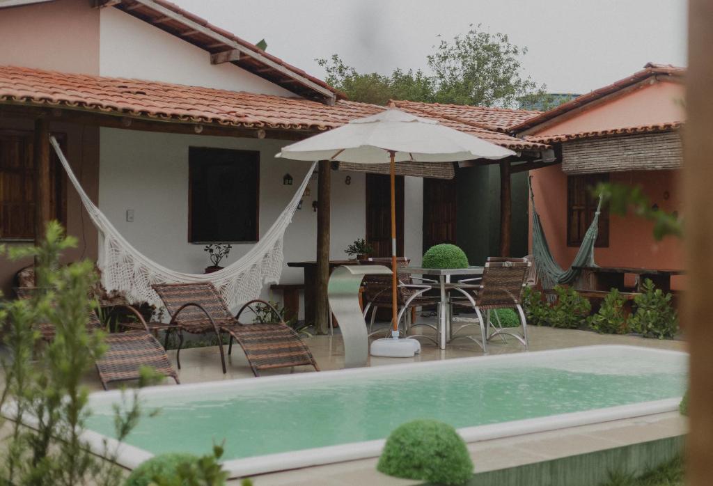 une maison avec une piscine et une table avec un parasol dans l'établissement Casinhas da Serena - Casa cacau, à Caraíva