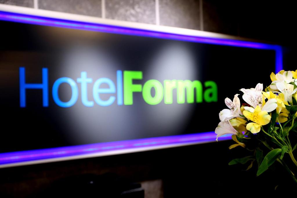 un televisor con el hite formma en la pantalla con flores en Hotel Forma en Piła