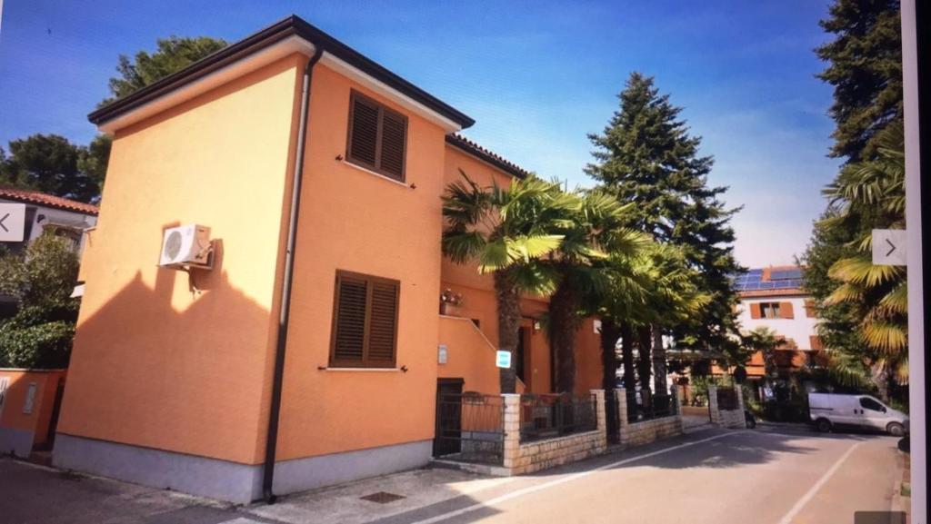 ein Gebäude in einer Straße mit Palmen daneben in der Unterkunft Apartman AMY 50m from the beach in Novigrad Istria