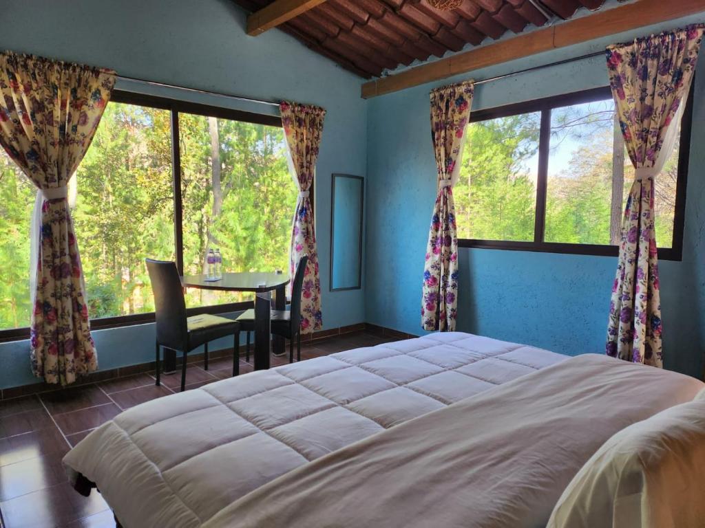 een slaapkamer met een groot bed en 2 ramen bij Rancho San Miguel in Villa del Carbón